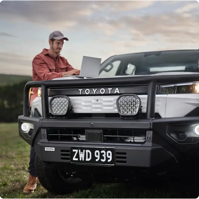 Person using laptop on Toyota pickup outdoors