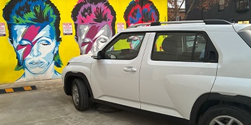 Hyundai INSTER in white parked in front of a David Bowie urban mural