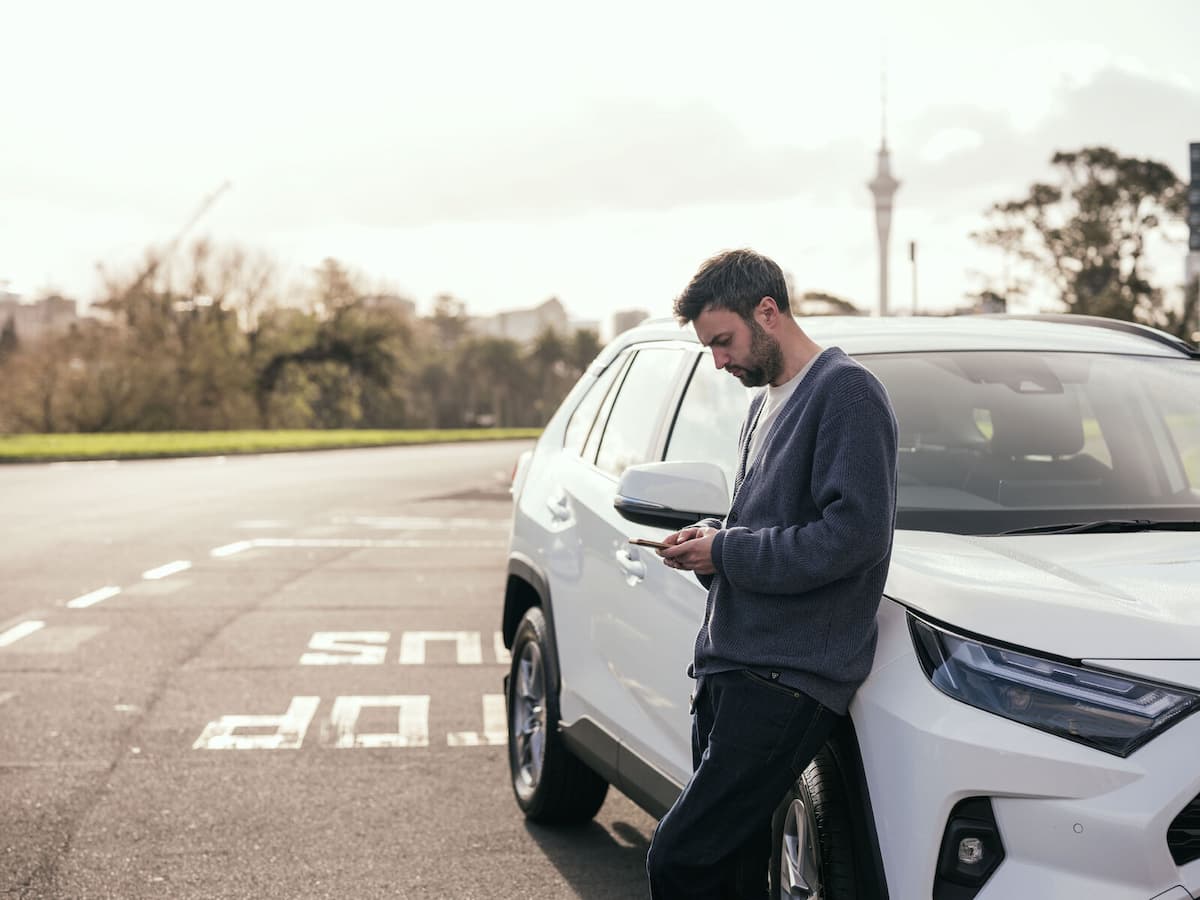 Person using a smartphone beside a parked SUV
