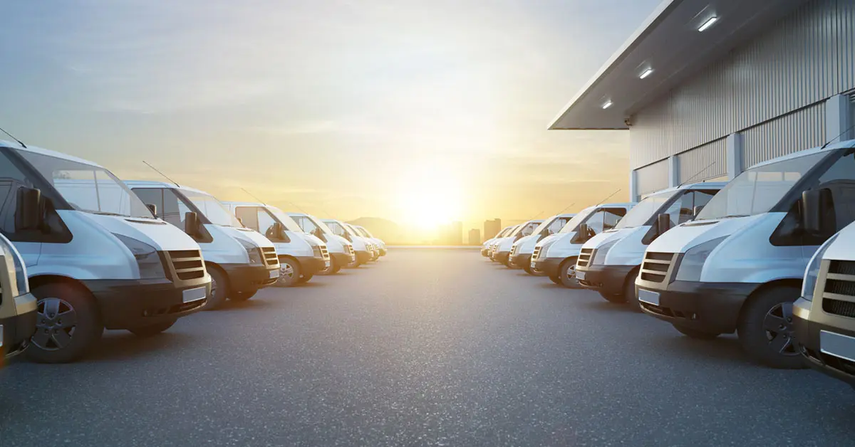 Commercial vans in two row with empty floor and factory building behide