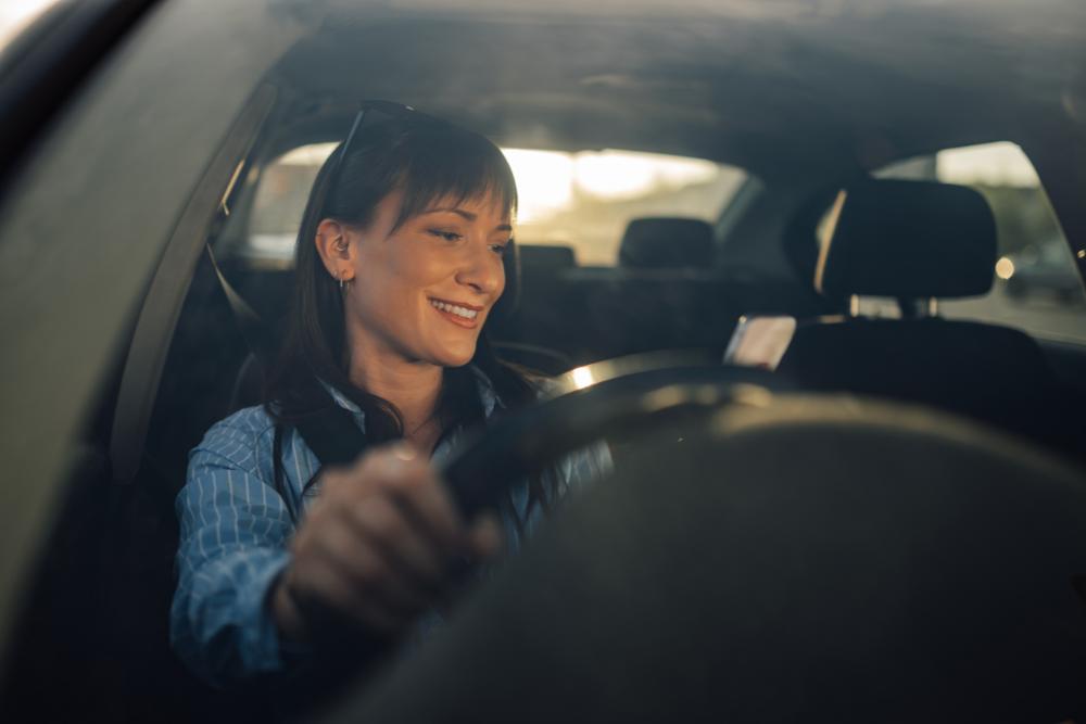Employee car benefit engagement Smiling woman driving a car, showing positive engagement with employee car benefits and company vehicle schemes