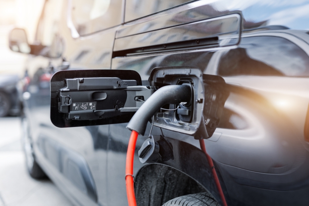 EV charging for fleets, a black electric van plugged in for charging, representing practical EV charging for fleets