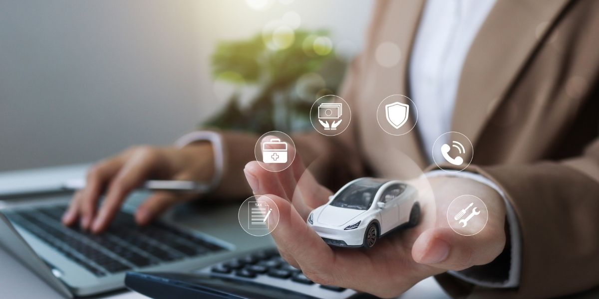 A hand holding a small white model car surrounded by floating digital service icons including insurance, maintenance, and support, above a laptop keyboard.