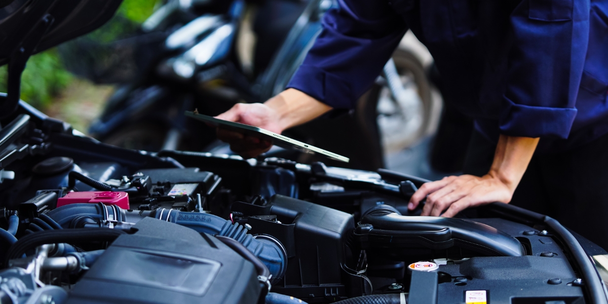 Fleet servicing vehicle maintenance, Mechanic inspecting a car engine with a tablet in hand, illustrating fleet servicing vehicle maintenance and digital workshop checks.
