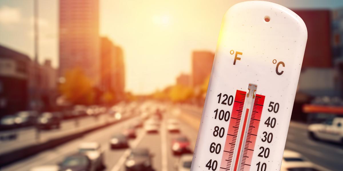 Summer driving tips UK header image A thermometer showing a high temperature reading beside a busy road full of traffic on a sunny day.